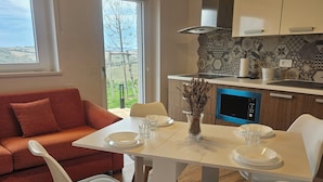 Cozinha moderna com micro-ondas, fogão e janela com vista para um jardim.