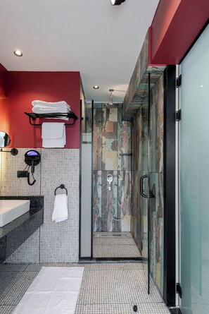 Ein modernes Badezimmer mit Duschkabine aus Glas, Waschbecken mit Spiegel und Handtuchhalter.