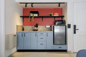 Eine kompakte Küche mit Mikrowelle, Kaffeemaschine und kleinem Kühlschrank.