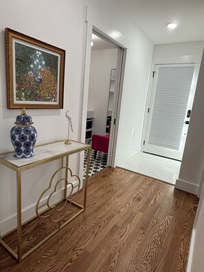 A hallway with a wooden floor, a white door, a mirror, and a framed painting on the wall. - The Eagle's Nest - 1 Min ATV Trail Access (Jacksboro)