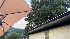 A covered outdoor seating area with a sectional sofa, coffee table, and decorative items.