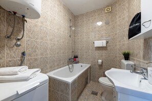 A bathroom with a bathtub, a sink, a toilet, and a towel rack. - Villa Nick-sunrise Deluxe Apartment (Konavle)