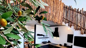 Cozinha moderna com bancada de pedra, painel de parede em madeira e planta pendente com folhas verdes e frutos amarelos.