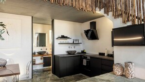 Uma cozinha moderna com bancada de pedra, armários pretos, uma ilha grande com pia e uma TV de tela plana fixada acima da ilha.
