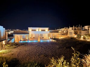 Ein modernes, zweistöckiges Gebäude mit Pool, Steinwänden und Blick auf die Umgebung.