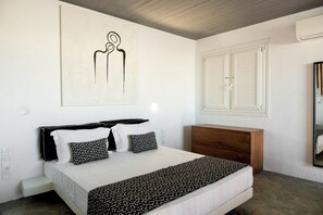 Un dormitorio con cama, mesita de noche, cómoda y una obra de arte en la pared.
