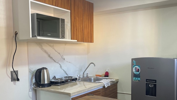 Una cocina equipada con microondas, estufa, pileta y dispensador de agua.