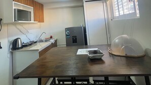 Una cocina equipada con microondas, refrigerador, lavaplatos y una mesa de comedor con bancos.
