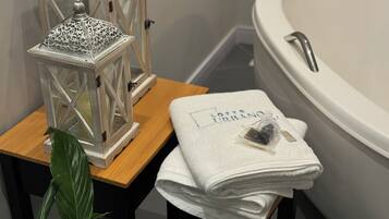 Un baño con una bañera blanca, un taburete de madera y una toalla blanca doblada, junto con un farol decorativo.