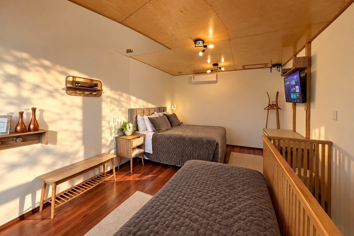 A bedroom with two beds, a wooden ceiling, a TV, and a bench.
