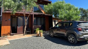 A modern building with a wooden facade, a car parked in front, and two potted plants.
