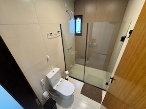 A modern bathroom with a glass-enclosed shower, a toilet, and a sink. - Lofts Urbano (Urubici)