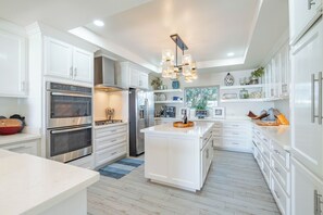 A modern kitchen with white cabinetry, stainless steel appliances, and a central island. - Luxury Beachfront Home: Pool, Large Groups, Boat, Water Sports (San Pedro)
