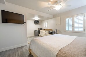 A bedroom with a bed, a ceiling fan, a TV mounted on the wall, and a window with blinds. - Luxury Beachfront Home: Pool, Large Groups, Boat, Water Sports (San Pedro)