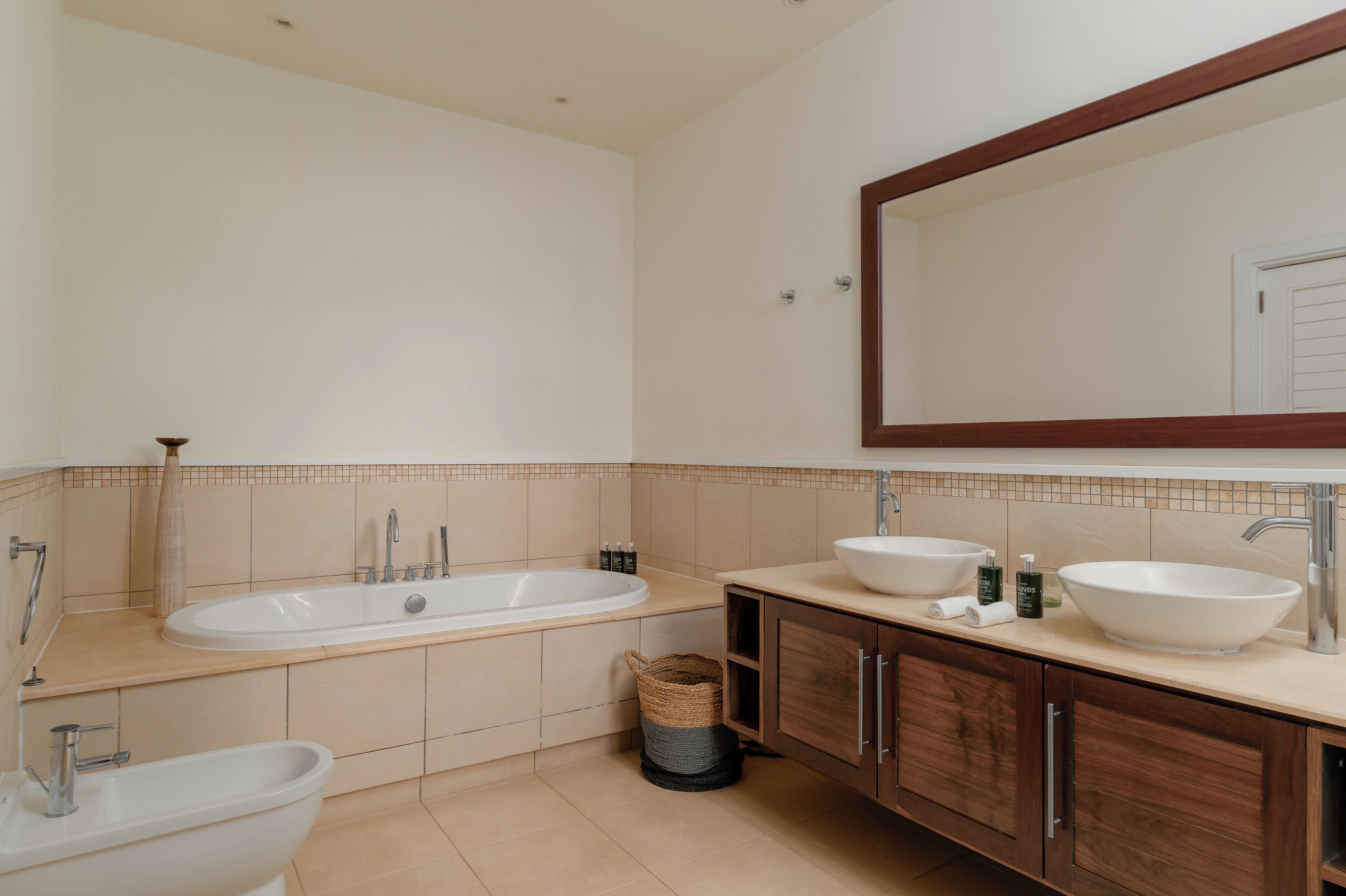 Un bagno con una vasca, due lavabi, un bidet e mobili in legno.