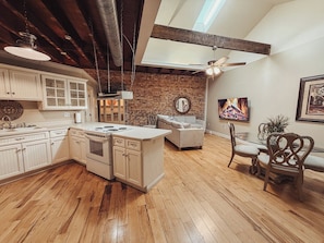 A kitchen with wooden cabinets, a central island, and a dining area with a sofa and chairs.