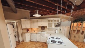 Una cocina con pisos de madera, armarios blancos, estufa y lavadora.