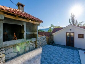 A building with a stone wall, a tiled roof, and a small attached structure with a door. - Rustic Villa in Gruda With Private Pool (Konavle)