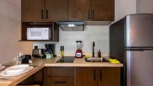 A kitchen with wooden cabinets, a stainless steel refrigerator, a microwave, a blender, and a coffee maker. - Deluxe studio in downtown Tulum with pool, rooftop and gymnasium (Tulum)