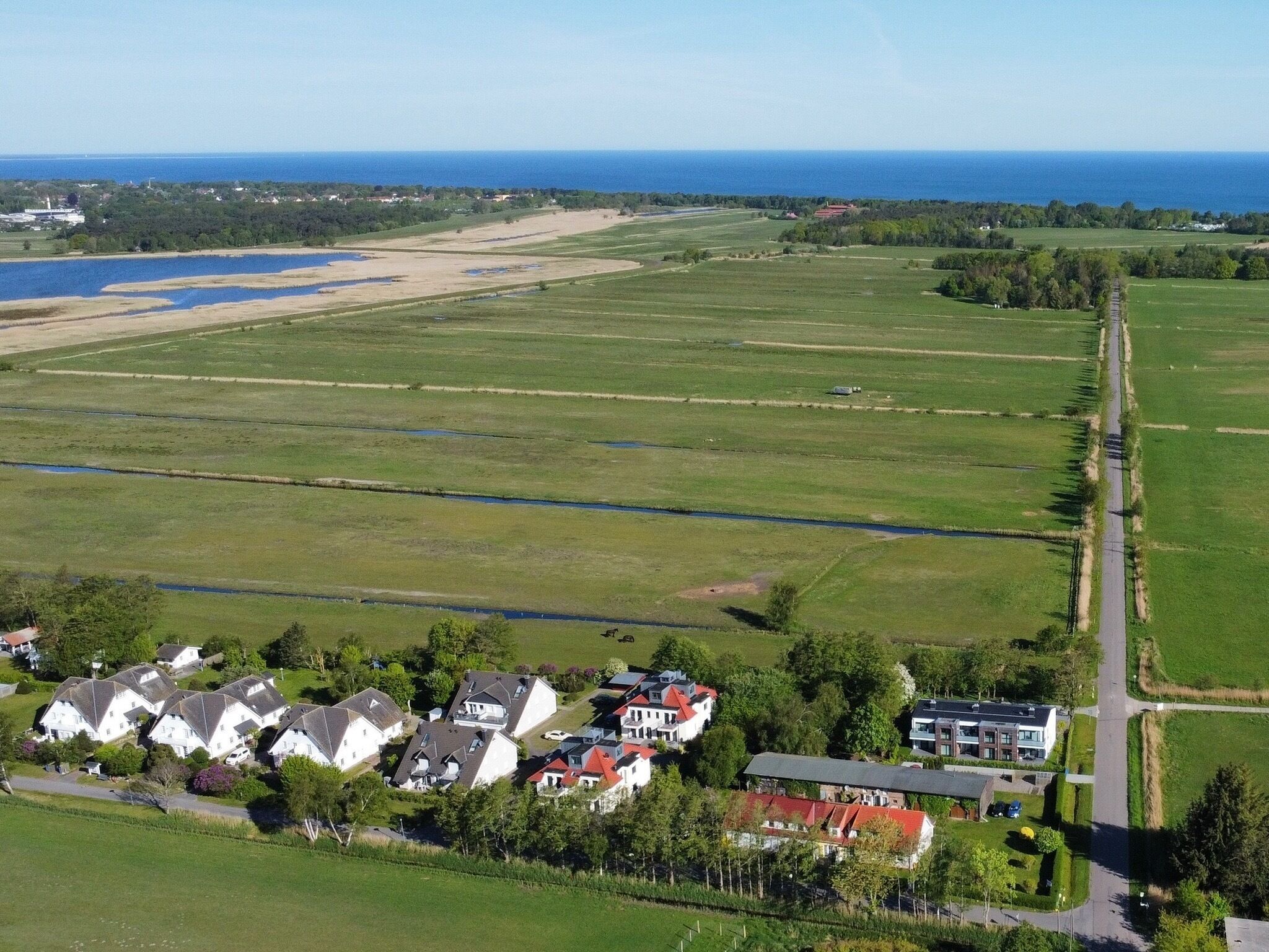 An aerial view of a residential area with houses, a road, and a large green field.