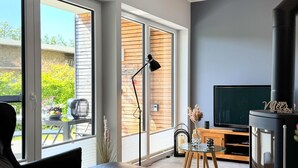 Una sala moderna con televisor grande, chimenea y comedor con mesa de vidrio.