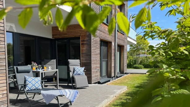 Un espacio al aire libre moderno con mesa, sillas y un banco cubierto.