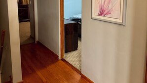 Ein Flur mit Holzboden, einer Tür zum Schlafzimmer und einem gerahmten Kunstwerk an der Wand.