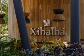 Un mur en bois portant l’inscription « Xibalba » et orné d’un motif stylisé représentant un oiseau.
