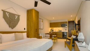 A modern hotel room with a large bed, a desk, a kitchenette, and a ceiling fan. - New Studio @ Xibalba | Private Pool + King Bed (Tulum)