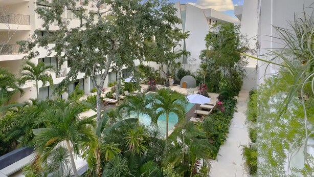 A pool surrounded by lush greenery and modern buildings. - New Studio @ Xibalba | Private Pool + King Bed (Tulum)