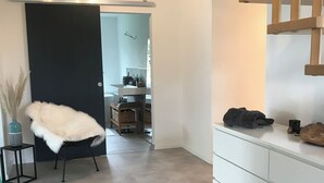 Ein modernes Interieur mit einer Treppe, einem weißen Schrank und einem Sessel mit einem flauschigen Kissen.