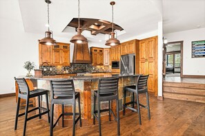 A kitchen with wooden cabinets, a central island with bar stools, and pendant lighting.
