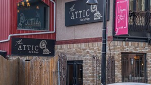 Rakennuksessa on kyltti, jossa lukee ”The Attic Bar & Stage”, ja erillinen kyltti, jossa lukee ”Taco Vegan Street Bar”.