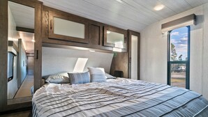 Ein Schlafzimmer mit einem großen Bett, einem Holz-Kopfteil und Blick durch ein Fenster.
