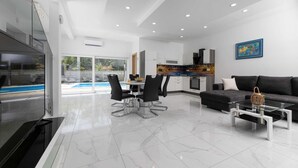 Una sala de estar moderna con comedor, cocina y vistas a la piscina.