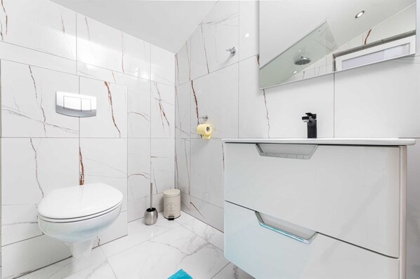 Et moderne badeværelse med toilet, bidet og et spejl over vasken.