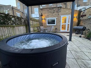 A hot tub in a backyard with a brick house in the background. - Stylish Kentish Town Home/Private Garden & Jacuzzi (London)