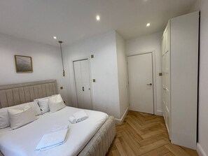 A bedroom with a bed, a wardrobe, and a door. - Stylish Kentish Town Home/Private Garden & Jacuzzi (London)