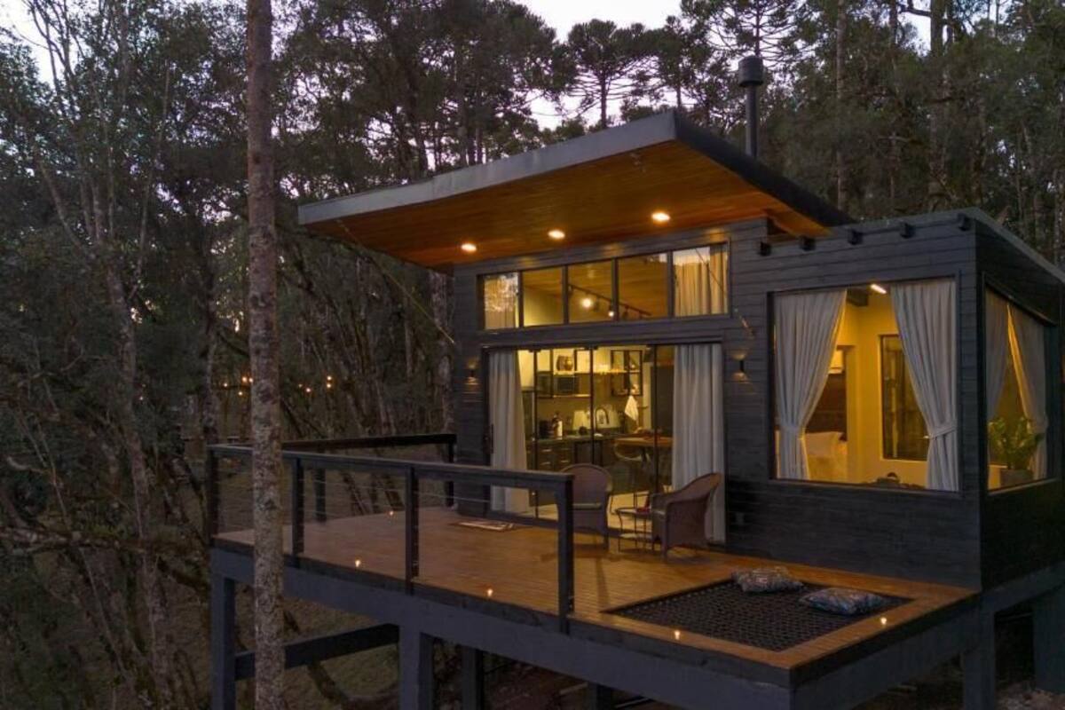 A modern cabin with a deck, large windows, and a dining area.