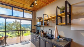 Una cocina moderna con una isla grande, techo de madera y vistas al campo.