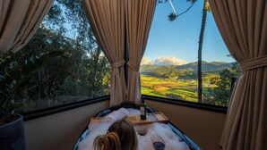 Una persona relajándose en una bañera con vistas a un paisaje a través de una ventana.