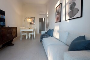 Ein modernes Wohnzimmer mit einer Couch, einem Esstisch mit Stühlen, einem Fernseher und Kunstwerken an den Wänden.