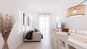 A modern living room with a sofa, dining table, chairs, and a TV. - A Designer Retreat "Zero Meters" from the Beaches of Versilia (Marina di Pietrasanta)