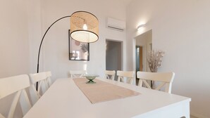A dining area with a white table, chairs, a woven pendant light, and a mirror on the wall. - A Designer Retreat "Zero Meters" from the Beaches of Versilia (Marina di Pietrasanta)