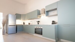 A modern kitchen with light blue cabinets, a built-in oven, and a stainless steel refrigerator. - A Designer Retreat "Zero Meters" from the Beaches of Versilia (Marina di Pietrasanta)