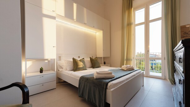 A bedroom with a bed, nightstands, a dresser, and a window with curtains. - A Designer Retreat "Zero Meters" from the Beaches of Versilia (Marina di Pietrasanta)