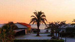 A coastal property with a house, palm trees, and a view of the sea at sunset. - A Designer Retreat "Zero Meters" from the Beaches of Versilia (Marina di Pietrasanta)