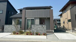 Um edifício residencial moderno de dois andares com telhado plano, janelas amplas e fachada de pedra.