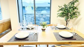 Mesa de jantar posta para quatro pessoas, com vista para a cidade através de grandes janelas.