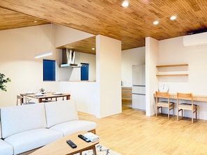 A modern living room with a sofa, a coffee table, and a dining area with a table and chairs.